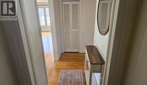 Ottawa apartment for rent - A hallway with a wooden floor and a rug in the middle.