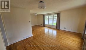 Ottawa apartment for rent - A room with wooden floors and a window with a view of a green area outside.