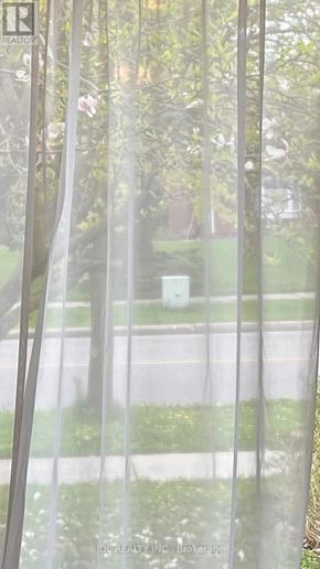 Toronto (Bayview Woods-Steeles) apartment for rent - A view of a street through a window with a curtain.