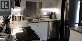 Kitchener condo for rent - A kitchen with a stove top oven, sink, and refrigerator.