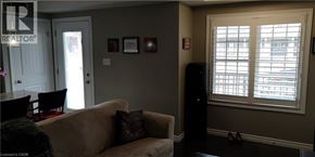 Kitchener condo for rent - A living room with a couch, chairs, and a window with blinds.