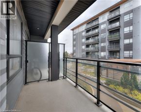 Waterloo condo for rent - A balcony with a glass railing and a view of a building across the way.