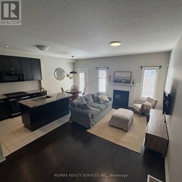 Hamilton (Mewburn) townhouse for rent - A living room with a grey couch and a fireplace.