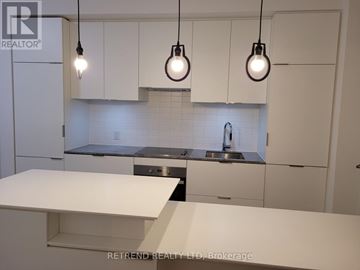 Toronto (Bay Street Corridor) condo for rent - A kitchen with white cabinets and a white island with three lights hanging above it.