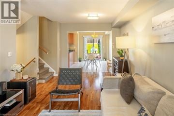 Milton townhouse for rent - A living room with a grey couch, a black chair and a wooden floor.