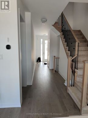 South-West Oxford townhouse for rent - A hallway with a staircase on the right and a person walking down the hallway.