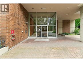 Burnaby apartment for rent - The image shows a glass door entrance to a building with a brick wall on one side and a fire extinguisher on the other.