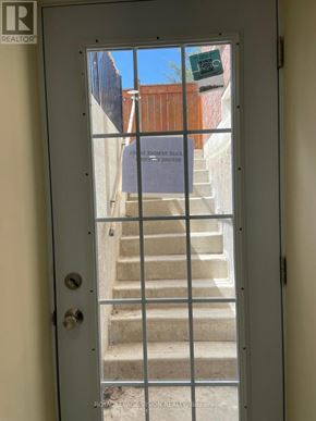 Oshawa (Windfields) apartment for rent - A door with a glass window showing a staircase.