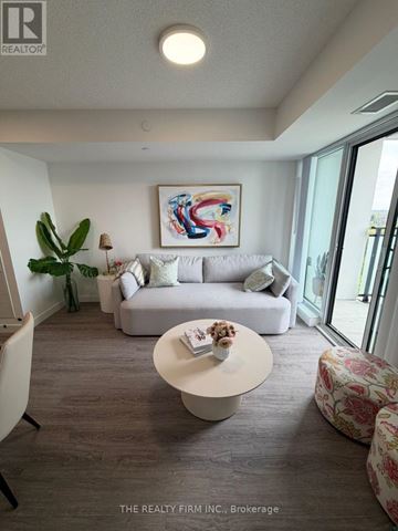 London East (East K) condo for rent - A living room with a grey couch, a white coffee table, and a painting on the wall.