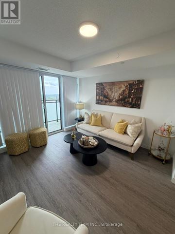 London East (East K) condo for rent - A living room with a white couch, a coffee table, and a painting on the wall.