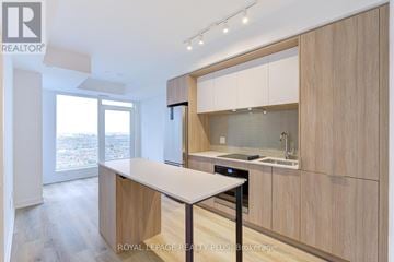 Mississauga (City Centre) condo for rent - A modern kitchen with wooden cabinets and a white island.
