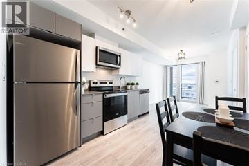 Burlington condo for rent - A modern kitchen with a stainless steel refrigerator and a dining table set for two.
