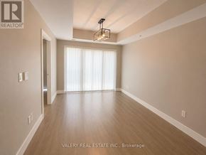 Kitchener condo for rent - A spacious room with wooden flooring and a chandelier hanging from the ceiling.