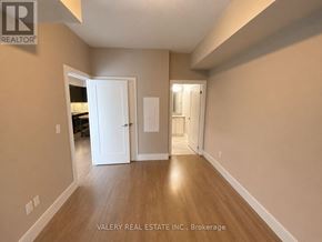 Kitchener condo for rent - A room with wooden floors and white walls, with a doorway leading to another room.