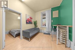 Ottawa multi-family for rent - A bedroom with a bed, a chair, and a table with a green wall.