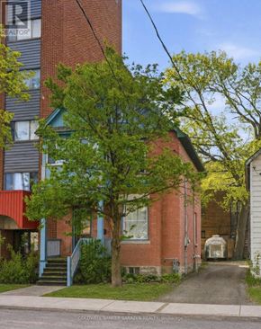 Ottawa multi-family for rent - A tree with green leaves is in front of a red brick building.