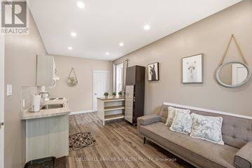 Ottawa multi-family for rent - A living room with a grey couch and a kitchen area in the background.