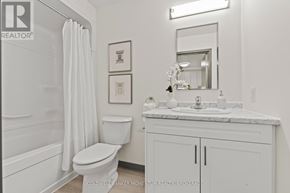 Thorold (Thorold Downtown) multi-family for rent - A white bathroom with a toilet, sink, and mirror.