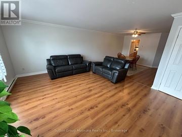 Huntsville (Chaffey) townhouse for rent - A living room with a black leather couch and a wooden floor.
