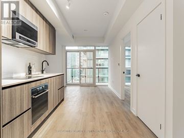 Toronto (Mount Pleasant West) condo for rent - A modern kitchen with wooden cabinets and a glass door leading to a balcony.
