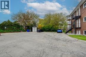 Kitchener apartment for rent - A parking lot with a blue car and a black car parked in front of a building.