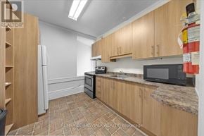 Ottawa multi-family for rent - A kitchen with wooden cabinets and a black microwave.