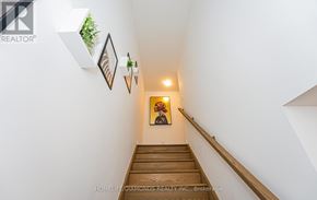 Niagara Falls (Downtown) townhouse for rent - A hallway with a wooden staircase and pictures on the wall.