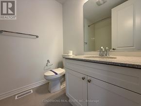 Markham townhouse for rent - A white toilet with a purple stripe is in a bathroom with a sink and mirror.