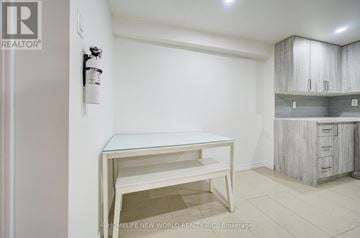 Markham (Milliken Mills East) apartment for rent - A white kitchen with a table and a cabinet.