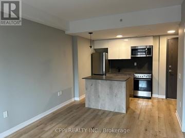 Oshawa (Central) condo for rent - A modern kitchen with a concrete island and stainless steel appliances.
