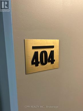 Oshawa (Central) condo for rent - A gold plate with the number 404 is mounted on a light-colored wall.