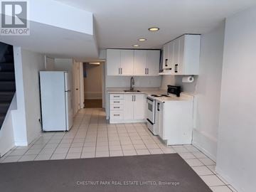 Toronto (North Riverdale) townhouse for rent - A kitchen with white appliances and cabinets is shown.