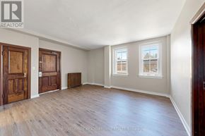 Halton Hills (Georgetown) apartment for rent - A room with wooden floors and white walls, with a window showing a view of a tree and a building.