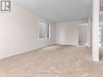 Ottawa apartment for rent - A spacious room with beige carpeting and white walls.