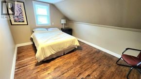 Windsor duplex for rent - A bedroom with a bed, chair, and wooden flooring.