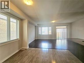 Hamilton townhouse for rent - A spacious room with a large window and a wooden floor.