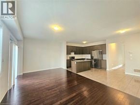 Hamilton townhouse for rent - A spacious living room with hardwood floors and a kitchen in the background.