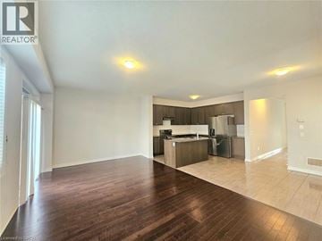 Hamilton townhouse for rent - A spacious living room with hardwood floors and a kitchen in the background.
