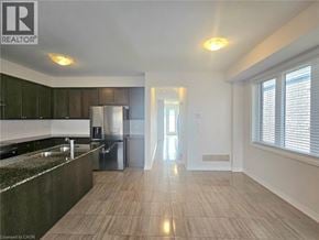 Hamilton townhouse for rent - A spacious kitchen with a refrigerator, sink, and wooden flooring.