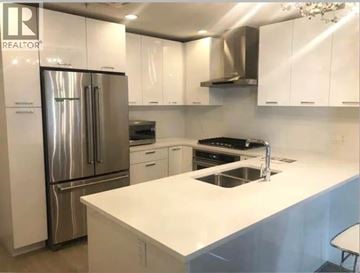 Vancouver apartment for rent - A white kitchen with a stainless steel refrigerator and a white countertop.