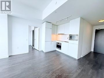 Toronto (Newtonbrook East) condo for rent - A spacious kitchen with white cabinets and a microwave above the oven.