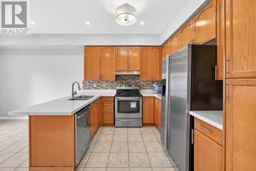 Mississauga (Meadowvale Village) townhouse for rent - A kitchen with wooden cabinets and a stone backsplash.