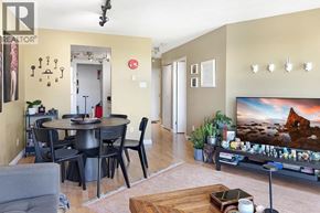 Vancouver apartment for rent - A living room with a grey couch, a black table and chairs, a flat screen TV, and a wooden coffee table.