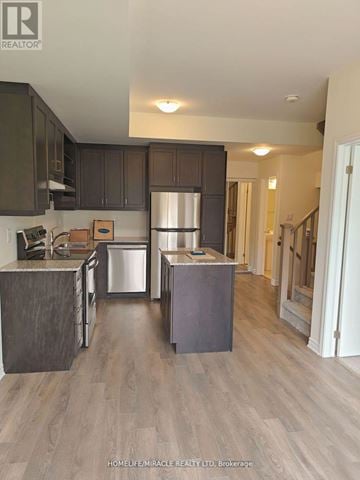 Toronto (Eglinton East) townhouse for rent - A kitchen with dark brown cabinets and a stainless steel refrigerator.