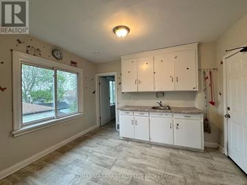 Welland (Lincoln/Crowland) multi-family for rent - A kitchen with white cabinets and a window overlooking a tree-lined street.