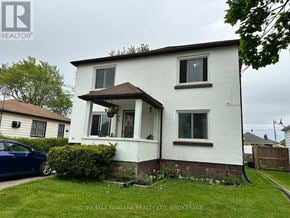 Welland (Lincoln/Crowland) multi-family for rent - A white house with a brown roof and a blue car parked in front.