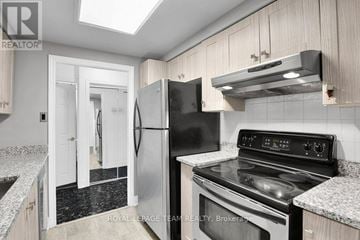 Ottawa condo for rent - A kitchen with a black refrigerator and stove top oven.
