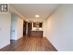 Richmond apartment for rent - A spacious room with wooden floors and a kitchenette in the background.