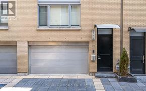 Toronto (Mount Pleasant West) townhouse for rent - A brick building with a closed grey garage door and a black door with a small plant in front.
