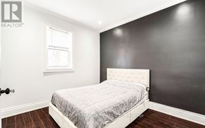 Hamilton (Industrial Sector) apartment for rent - A bedroom with a bed, wooden floors, and a window.